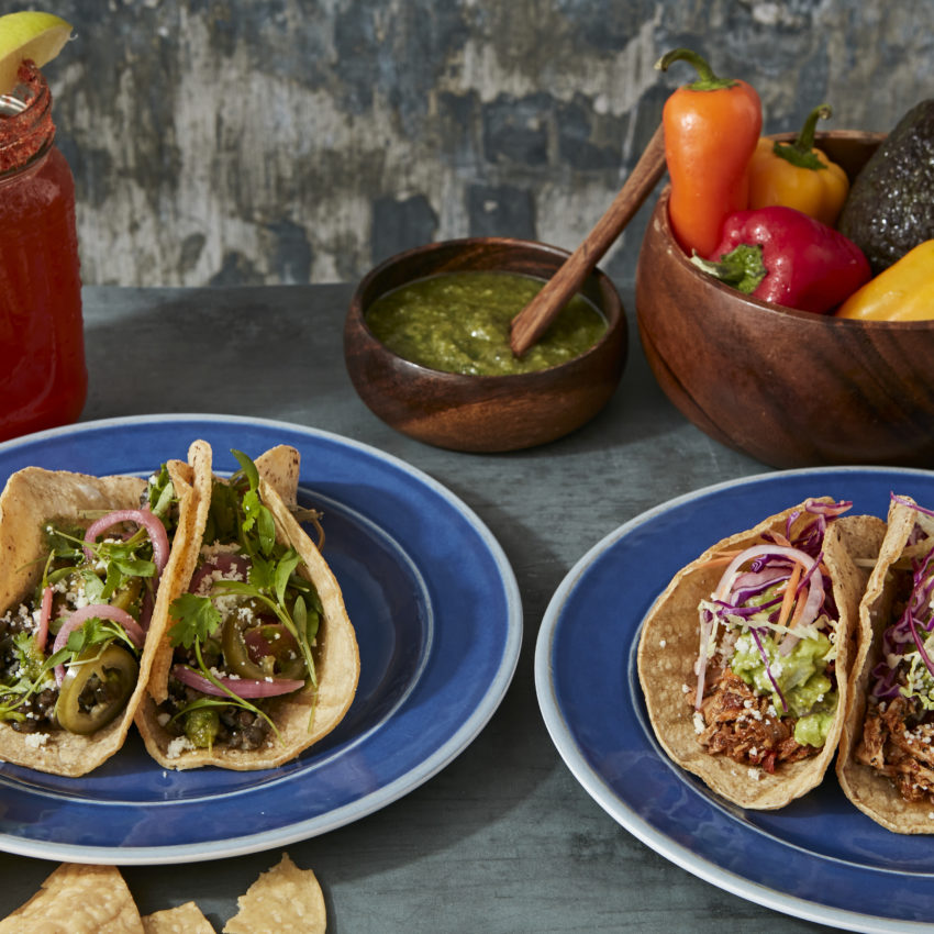Plated tacos, salsa verde and chips, michelada