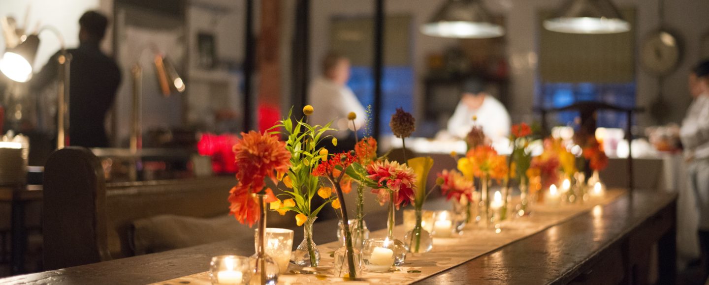 Florals and candles on a runner down a wooden kitchen table