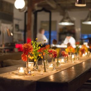 Florals and candles on a runner down a wooden kitchen table