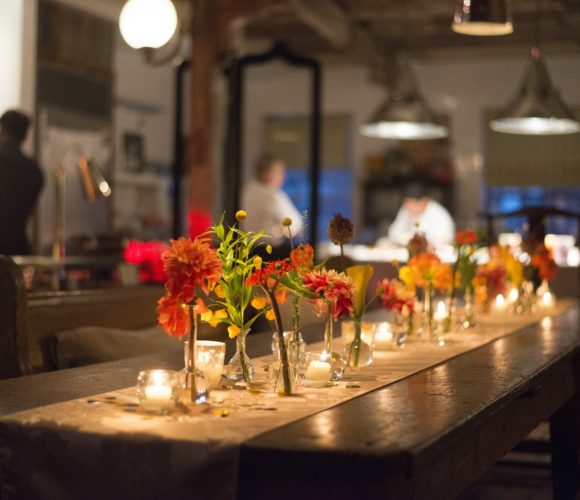 Florals and candles on a runner down a wooden kitchen table
