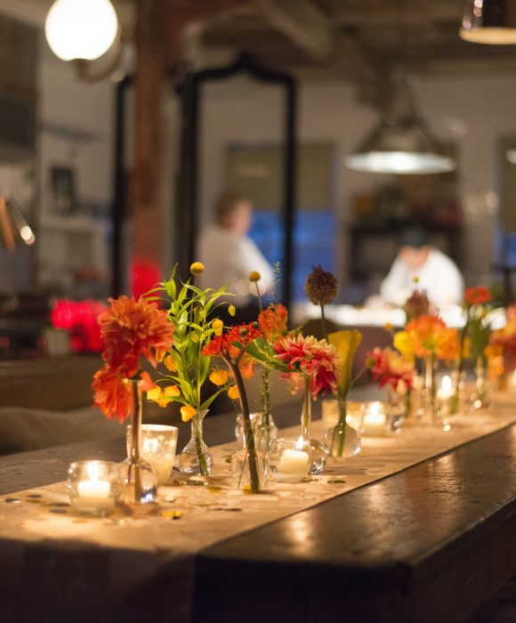 Florals and candles on a runner down a wooden kitchen table